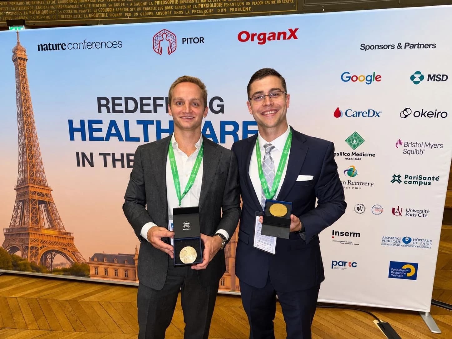 Austin Schoeffler and a colleague holding their Best Abstract medals in front of the Redefining Healthcare in the Age of AI banner